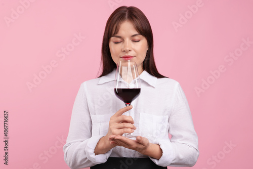 Fényképezés Professional sommelier tasting red wine on pink background