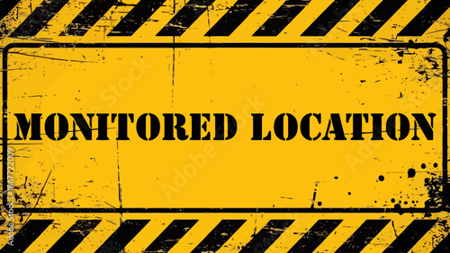 Distressed Yellow and Black "MONITORED LOCATION" Stencil Security Sign with Grunge Texture and Hazard Stripes