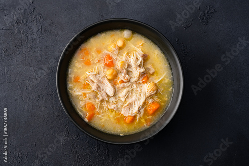 Delicious chicken soup with chickpeas served on an old black stone table.	
