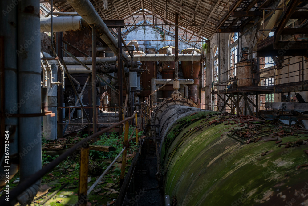 Fototapeta premium Derelict industrial hall of an abandoned Italian sugar mill. Large warehouse ruins with decaying walls and urban exploration atmosphere