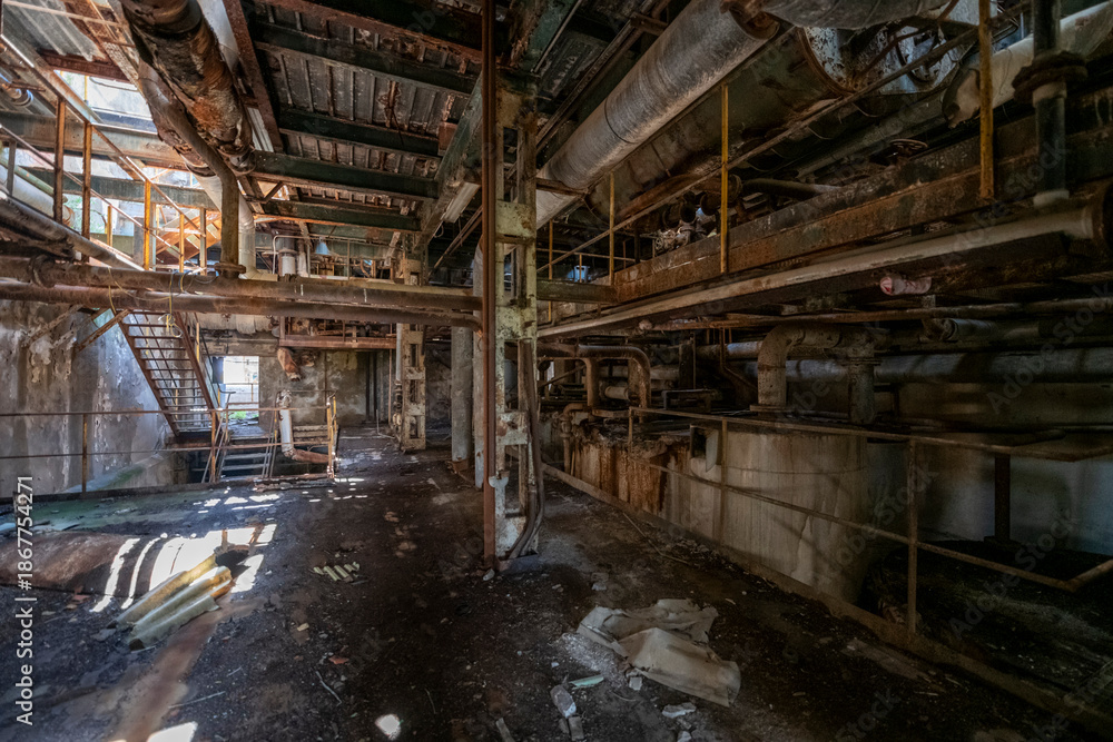 Fototapeta premium Derelict industrial hall of an abandoned Italian sugar mill. Large warehouse ruins with decaying walls and urban exploration atmosphere