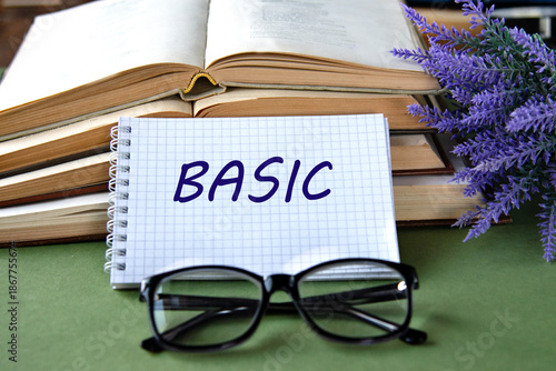 Notebook with BASIC text on a green background with books and glasses