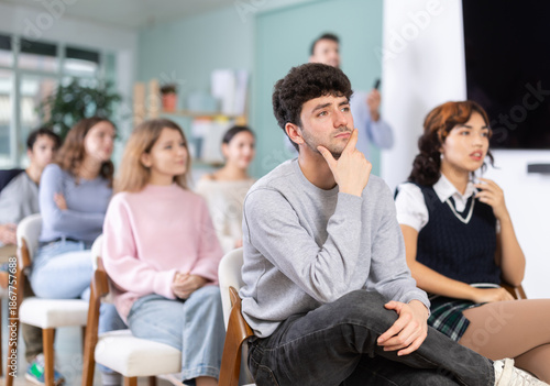 Group of young people attend classes to prepare for exams, they participate in lectures and discussions. Students carefully watch the presentation