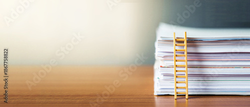 Stack of documents with small wooden ladder on desk, career growth, bureaucracy pressure, corporate ladder, office life, paperwork overload, productivity stress, administrative burden
