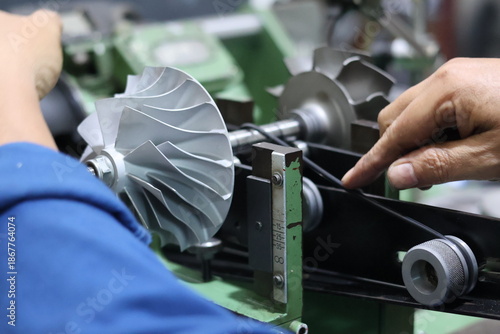 Obraz na plátně Technician hands adjusting a turbocharger compressor wheel on a dynamic balancing machine, precision mechanical engineering and maintenance process in a workshop