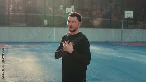 Dynamic shot of a bearded basketball player pointing to the camera with on hand, holding the other hand to his heart. A vibrant blue court. Black spot outfit.