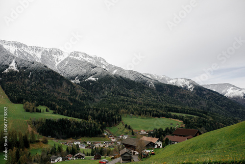 Alpine village nestled in a valley with snow-capped mountains and evergreen forests