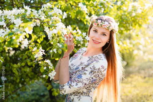 Portrait of beautiful woman in blooming bush with white flowers