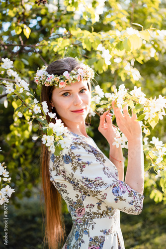 Portrait of beautiful woman in blooming bush with white flowers