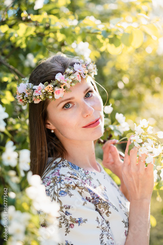 Portrait of beautiful woman in blooming bush with white flowers