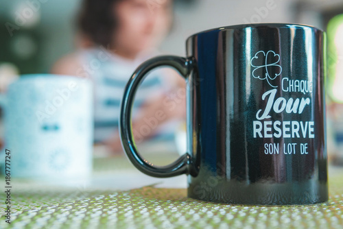 Close-up of a coffee cup with a cheerful phrase in French