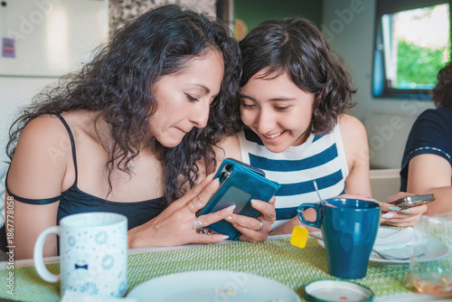 Happy young Latin women enjoying a healthy breakfast while seated in the dining room of their modern apartment. Healthy lifestyle and nutrition concept.