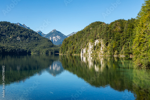 Calm Alpsee Lake With Mountain Reflections And Green Forest in Schwangau, Germany