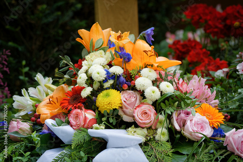 Fotografija Solemn floral tribute with roses and lilies placed at a grave, featuring a blurr