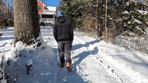 young man walking up the driveway after snow storm in January in New Jersey