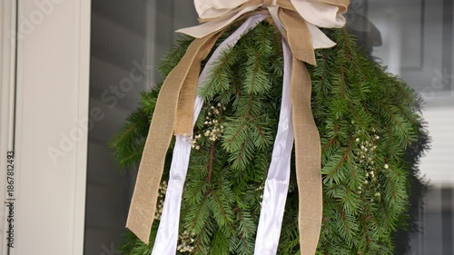 Camera moves upward showing a natural Christmas decoration made from real fir branches. Festive holiday detail with cozy winter atmosphere and handmade charm. medium wide shot