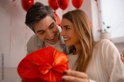 Romantic couple looking at each other holding heart shaped gift box
