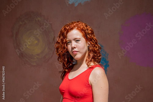 A woman with red hair is wearing a red tank top