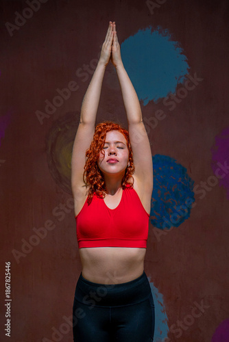 A woman in a red tank top is doing yoga poses