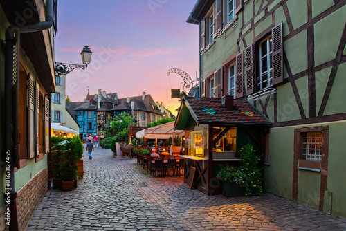 Принти на полотні Cobblestone streets of sidewalk cafes and shops illuminated at twilight in the Petite Venise district of the Alsatian city of Colmar, France