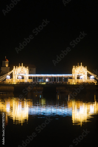 Illuminated bridge and waterfront area during night celebration at a lake location