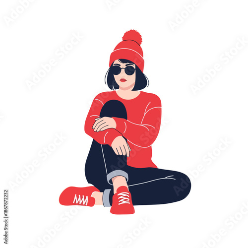 Stylish young woman in red beanie, sweater, and sneakers sitting cross-legged.