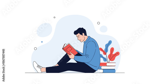 Young man sitting on the floor and leaning against a stack of books while engrossed in reading a red book in a peaceful setting.