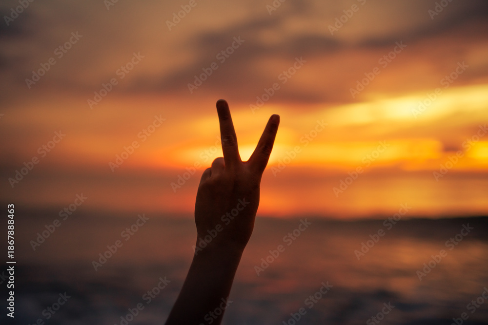 Fototapeta premium Peace Sign Silhouette at Sunset by the Ocean 