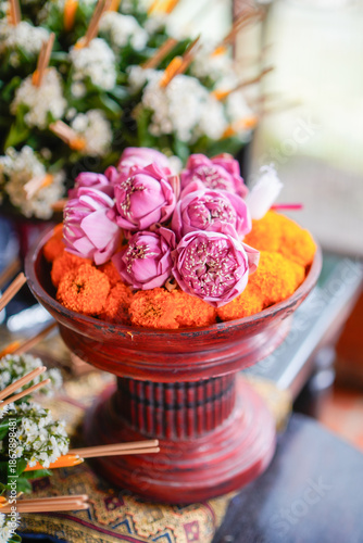 Beautiful pink lotus buds and marigolds on a traditional red wooden pedestal tray for sacred Thai ceremony.