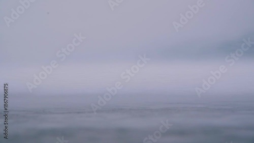 A close-up, shallow depth of field, low angle, and slow motion. Snow is blown across the frozen surface of the ice by the wind. An opening shot for a film or video.