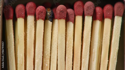Macro shot of matches packed tightly in a box, with red tips and wooden sticks