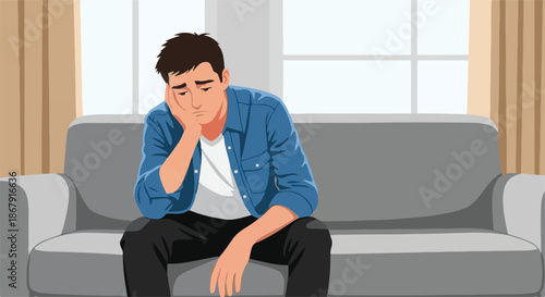 A young man sitting on a couch looking distressed and dejected, reflecting a feeling of sadness or disappointment