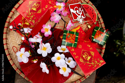 Vibrant and festive flat lay of Vietnamese Tet decorations on a bamboo tray with sticky rice cake, red envelopes, and peach blossoms
