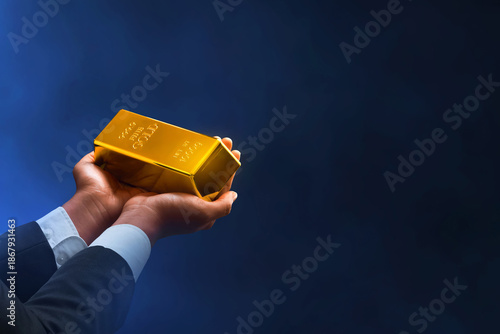 Businessman hand holding shiny gold bar on dark background
