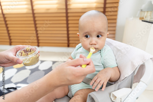 Fotografía Close-up of baby being spoon fed with homemade baby food while sitting in high chair