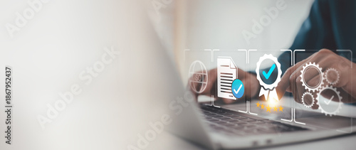 Fotografie Businessman is reviewing virtual icons on a laptop, representing quality control, business excellence, and certification standards