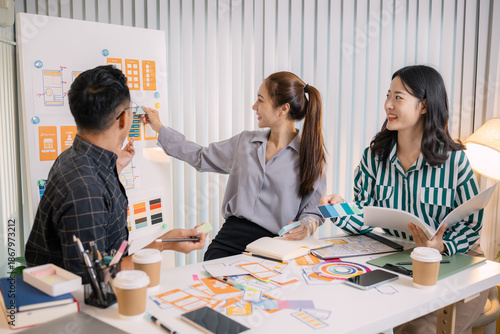 Designers having a UX/UI planning meeting to refine mobile app layouts and user flow. They collaborate closely to create functional and visually appealing interface solutions.