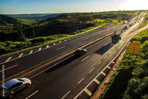 Wallpaper Mural Marilia, SP, Brazil, November 19, 2025. Highway SP-294 in Marilia, at sunset. Intense traffic of cars and trucks flows through the green landscape, illuminated by the golden hour light. Torontodigital.ca