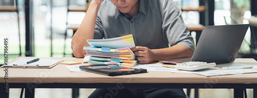 Overwhelmed by Workload: A person sits at a desk, buried beneath a mountain of paperwork. The scene conveys stress and pressure that comes with a heavy workload. 