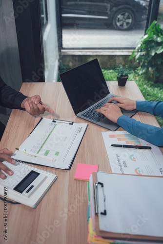 Business Collaboration: Business professionals engaging in collaborative work with documents, a laptop, calculator, and other necessary items in a workspace.