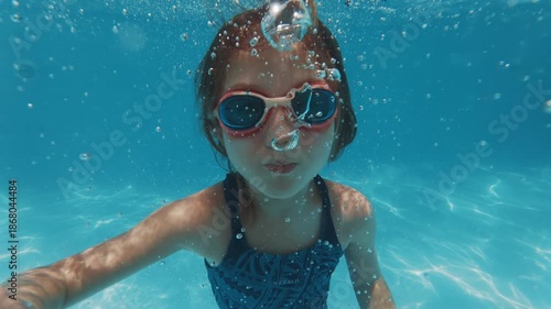 Girl swims underwater in the pool. Pre teen girl feels herself comfortable and relaxed underwater. Little girl dives and swims in the pool