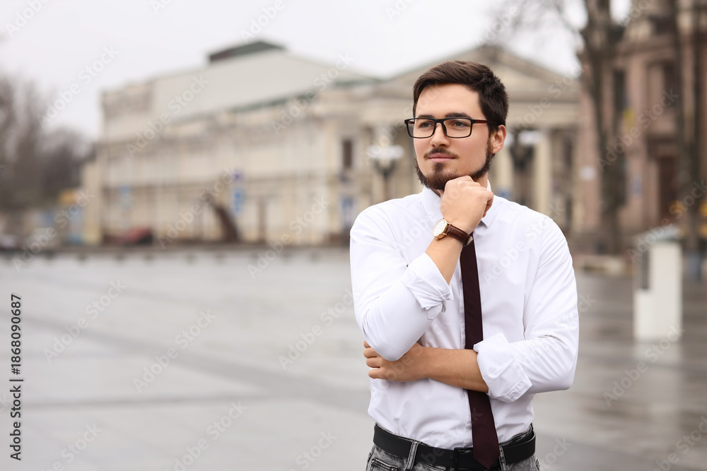 Fototapeta premium Thoughtful businessman in eyeglasses on city square