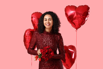 Beautiful African-American woman with roses and heart-shaped balloons on pink background. Valentine's day celebration