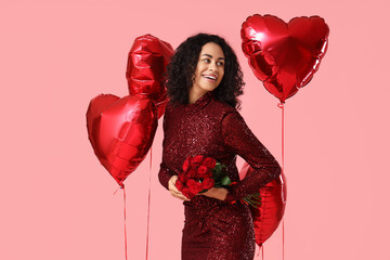 Beautiful African-American woman with roses and heart-shaped balloons on pink background. Valentine's day celebration