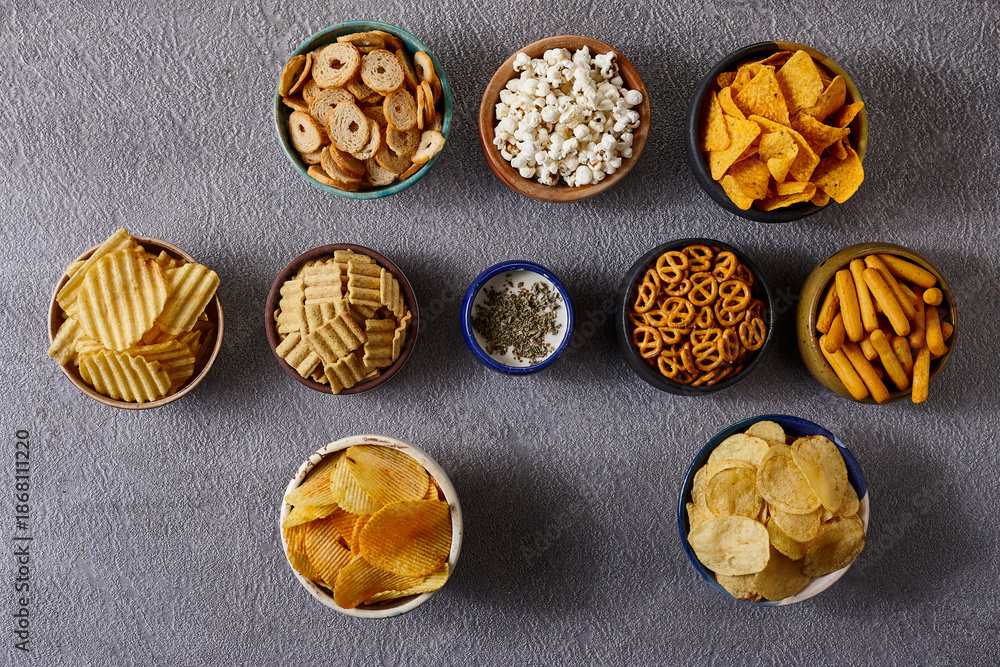 Fototapeta premium Assorted snacks in pottery bowls on grey background