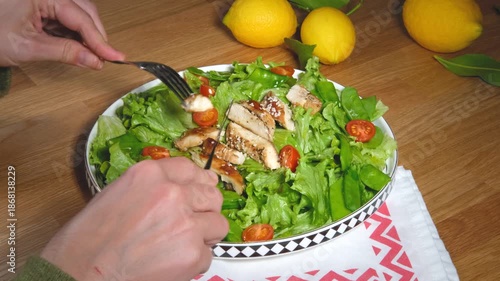 green salad with grilled chicken fillet, woman hands, eating healthy food