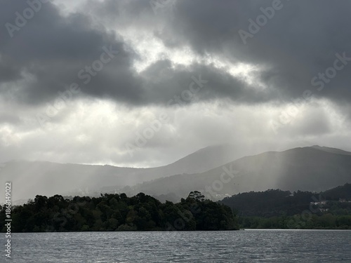 Dramatic light rays over the cloudy river Minho mountainous landscape near Eiras, O Rosal, Galicia, Spain, April 2025