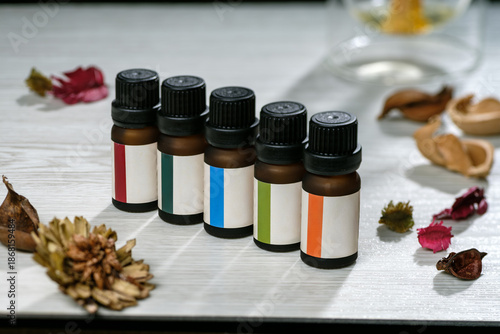 photograph of many essential oil bottle with colored label with scene of wooden table and dried flower