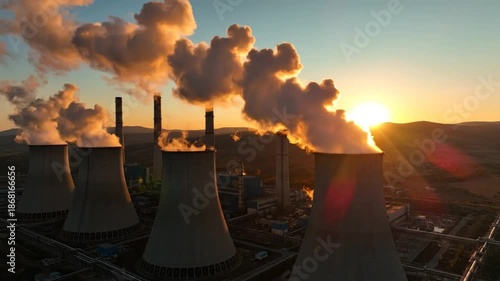 Industrial power plant emitting clouds of smoke into the sky during a golden sunset, environmental impact concept