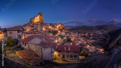 Illuminated medieval village of Frias at twilight with castle on rock in Burgos Spain